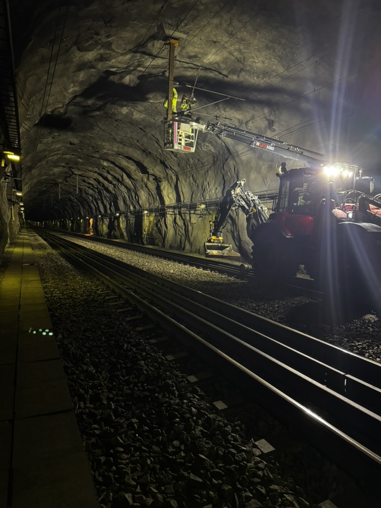 Arbete i järnvägstunnel med arbetslift och arbetare i varselkläder